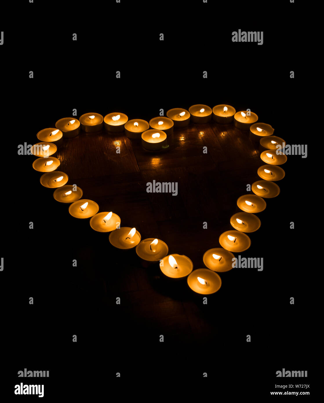 Herzform aus Tee - Kerzen auf einem schwarzen Hintergrund Stockfoto
