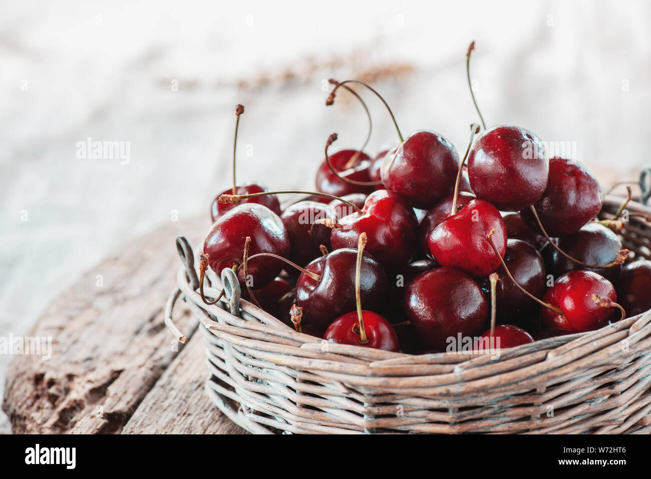 Dunkle rote reife große Kirschen in einem Weidenkorb auf einem Holztisch, selektive konzentrieren. Close Up. Kopieren Sie Platz. Stockfoto