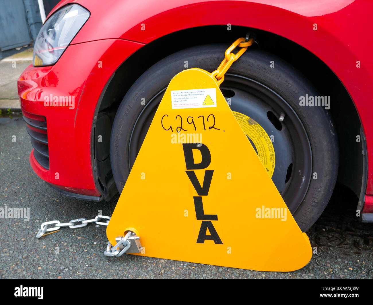 DVLA Rad Zange zu einem roten UK Auto, der nicht die Straße Steuer Versicherung oder jährliche MOT Test bezahlt haben Stockfoto