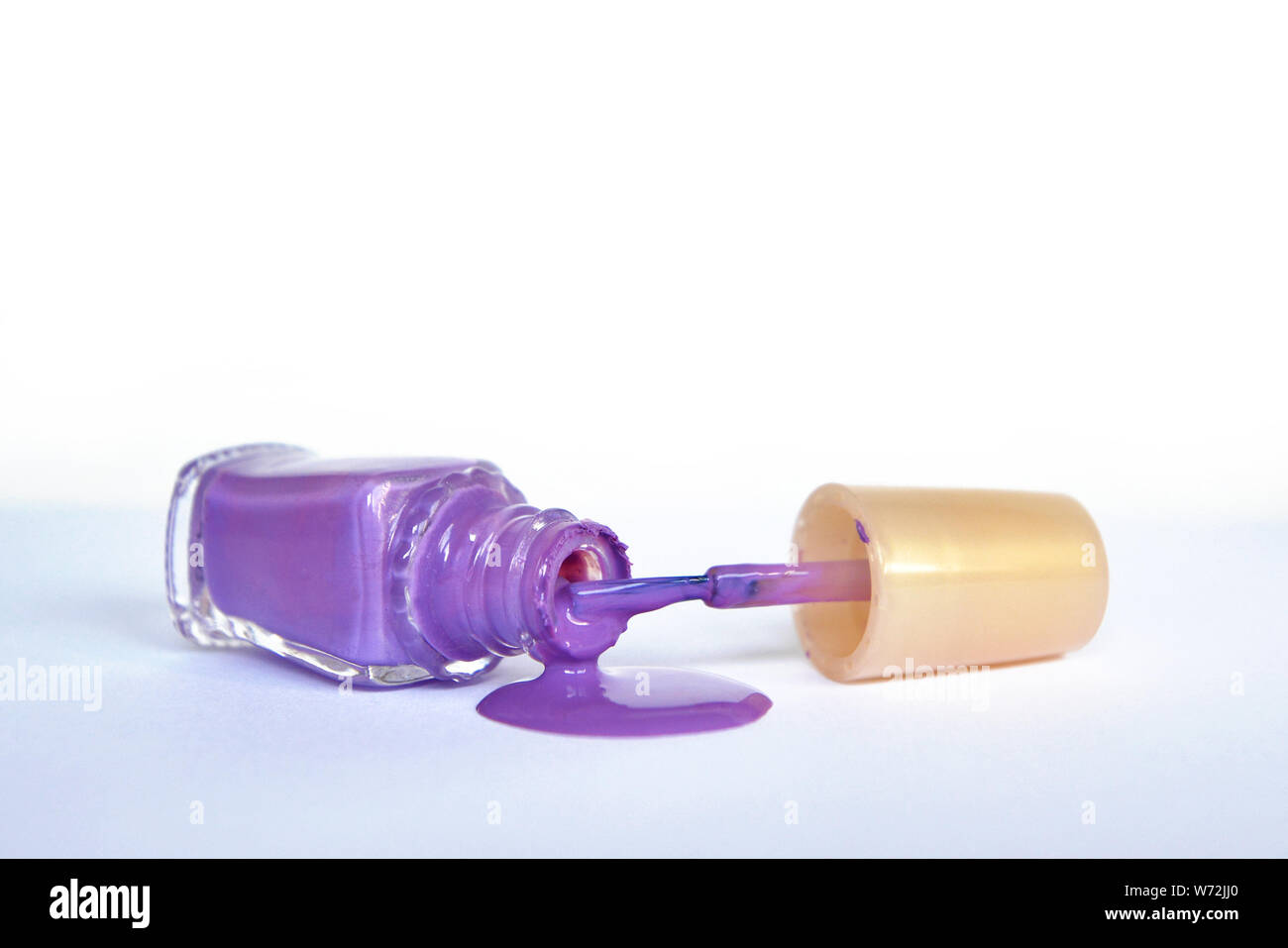 Öffnen lila Nagellack Flasche liegen auf der Seite mit dem verschütteten  Nagellack Gießen auf weißem Hintergrund Stockfotografie - Alamy