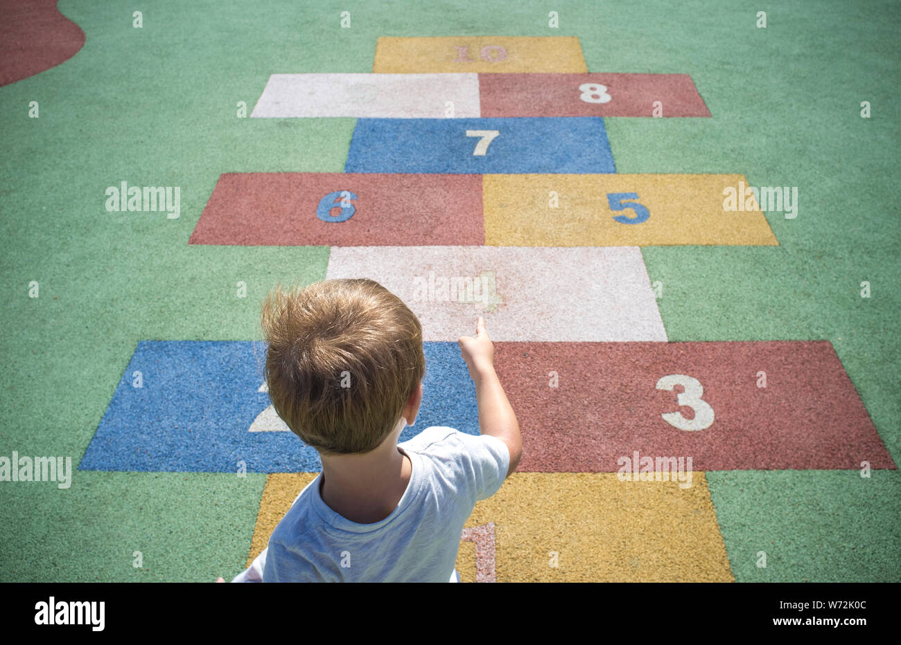 Jungen lernen Zahlen an Gummi Hopse. Zahlen auf dem Bürgersteig. Frühe Bildung in Mathematik-, Schreib- und Rechenfertigkeiten Konzept für Kinder Stockfoto