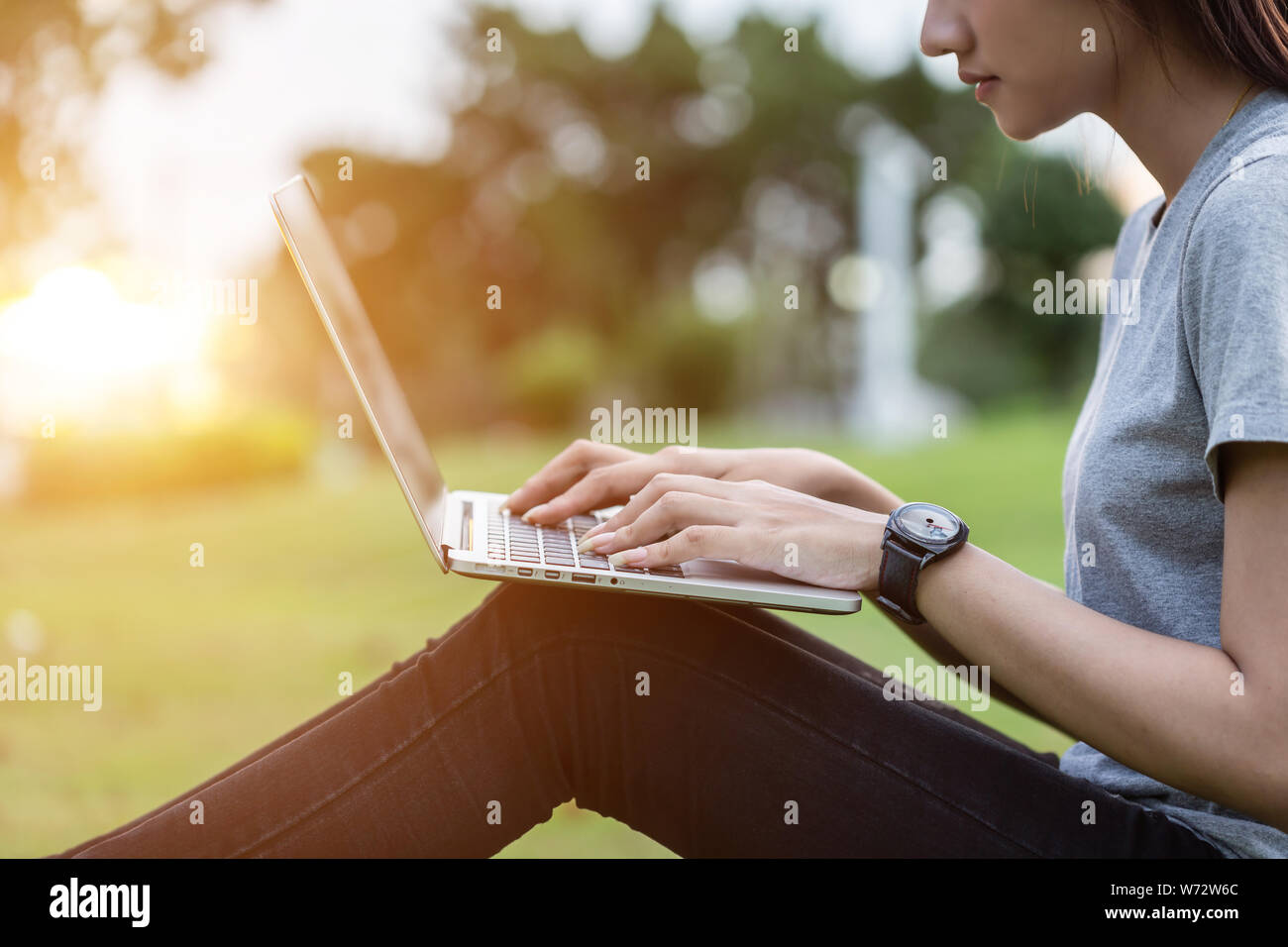 Nahaufnahme, Frau im Park bei Sonnenuntergang sitzen und mit Laptop Stockfoto