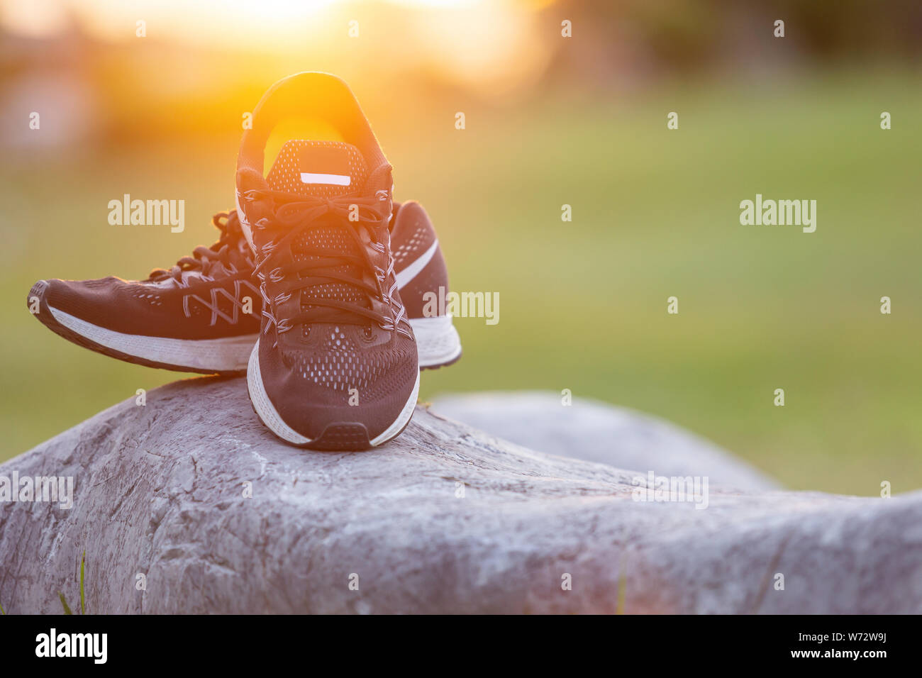 Close up neue Paare schwarz Schuhe/Sneaker Schuhe auf der grünen Wiese im Park bei Sonnenuntergang. Worm Ton, Sonnenlicht und lens flare Effekt w Stockfoto