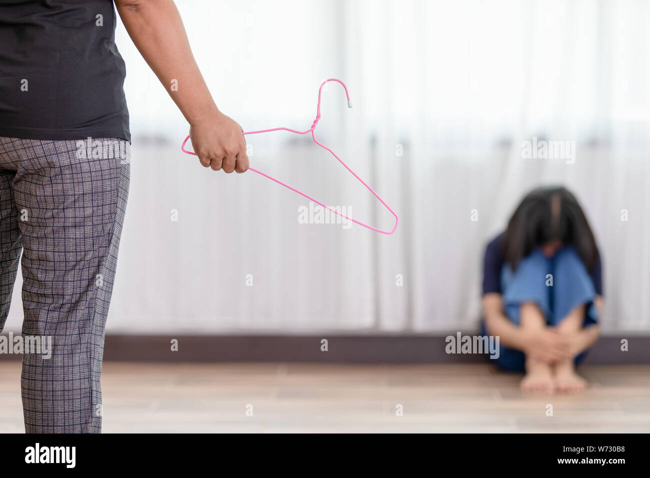 Die Mutter ihre Tochter zu bestrafen. Frau mit Kleiderbügel und ihre  Tochter sitzen auf dem Boden. Bestrafung Konzept Stockfotografie - Alamy