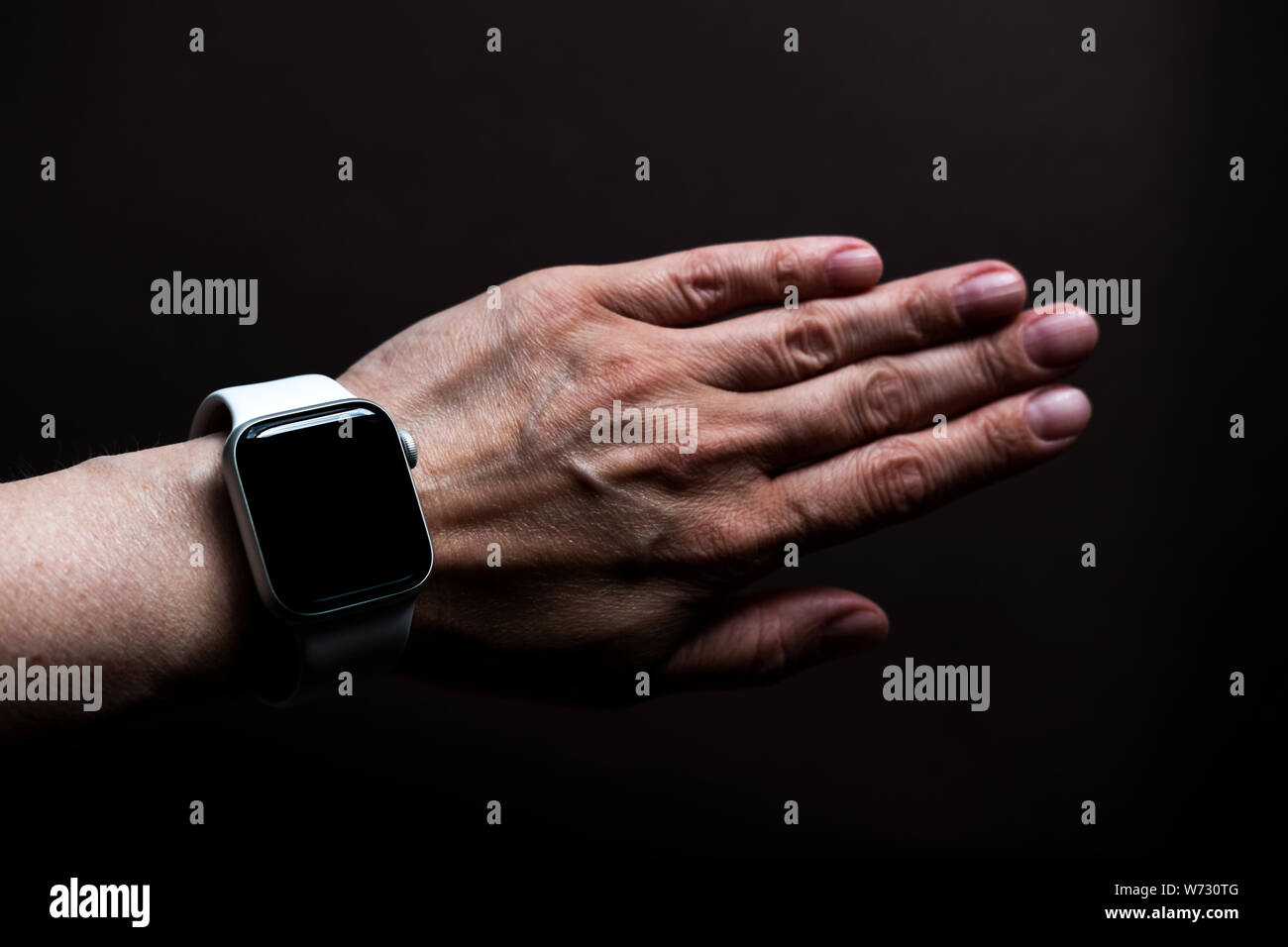 Tschechow, Russland - Juli 19, 2019: Apple Watch Serie 4 Farbe Weiß mit Hand. Eine neue Uhr aus der Firma Apple closeup auf dunklem Hintergrund isoliert Stockfoto