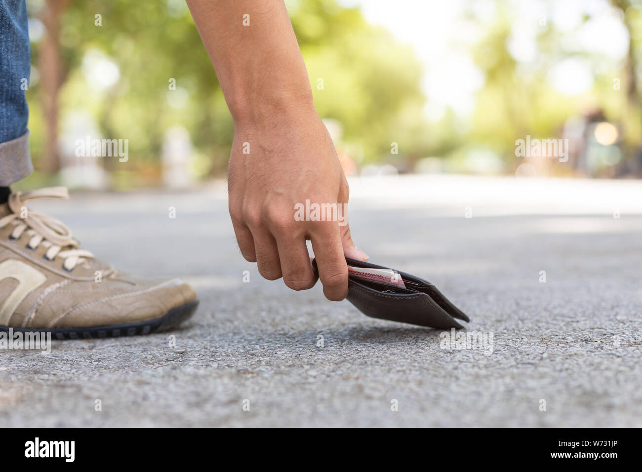 Asiatischer Mann picking schwarzen Mappe auf der Straße in touristische Attraktion. Wallet Konzept zu verlieren. Stockfoto