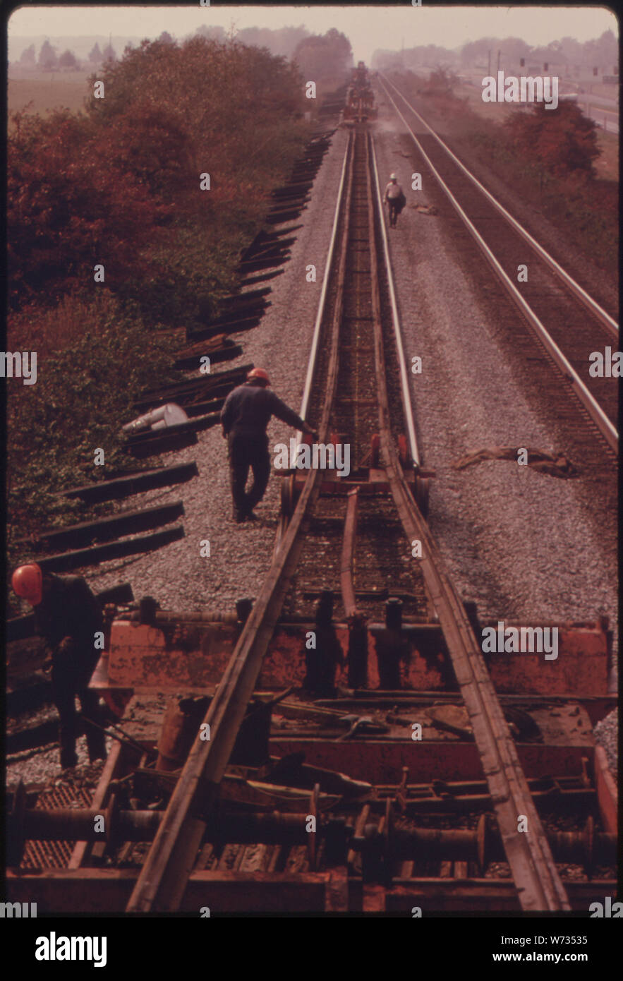 SOUTHERN RAILWAY VORFAHRT ARBEIT MANNSCHAFT, NIMMT ALTEN SPUR NACH DEM AUSTAUSCH MIT viertel Meile ABSCHNITTE DER NEUEN schienen. An einem guten Tag, WENN DIE BESATZUNG MUSS NICHT anhalten, nur ARBEITEN ZU VIELE MALE ZU LASSEN ZÜGE auf parallelen Bahnen, SIE KÖNNEN ETWAS WENIGER ALS ZWEI MEILEN VON GESCHWEISSTEN TITEL PRO TAG. 1974 südliche HATTE EINEN DURCHSCHNITT VON VIER MANNSCHAFTEN NUMMERIERUNG 50 bis 55 Männer jedes ARBEITEN AN DER ANLAGE 10,531 Meilen Schiene Stockfoto