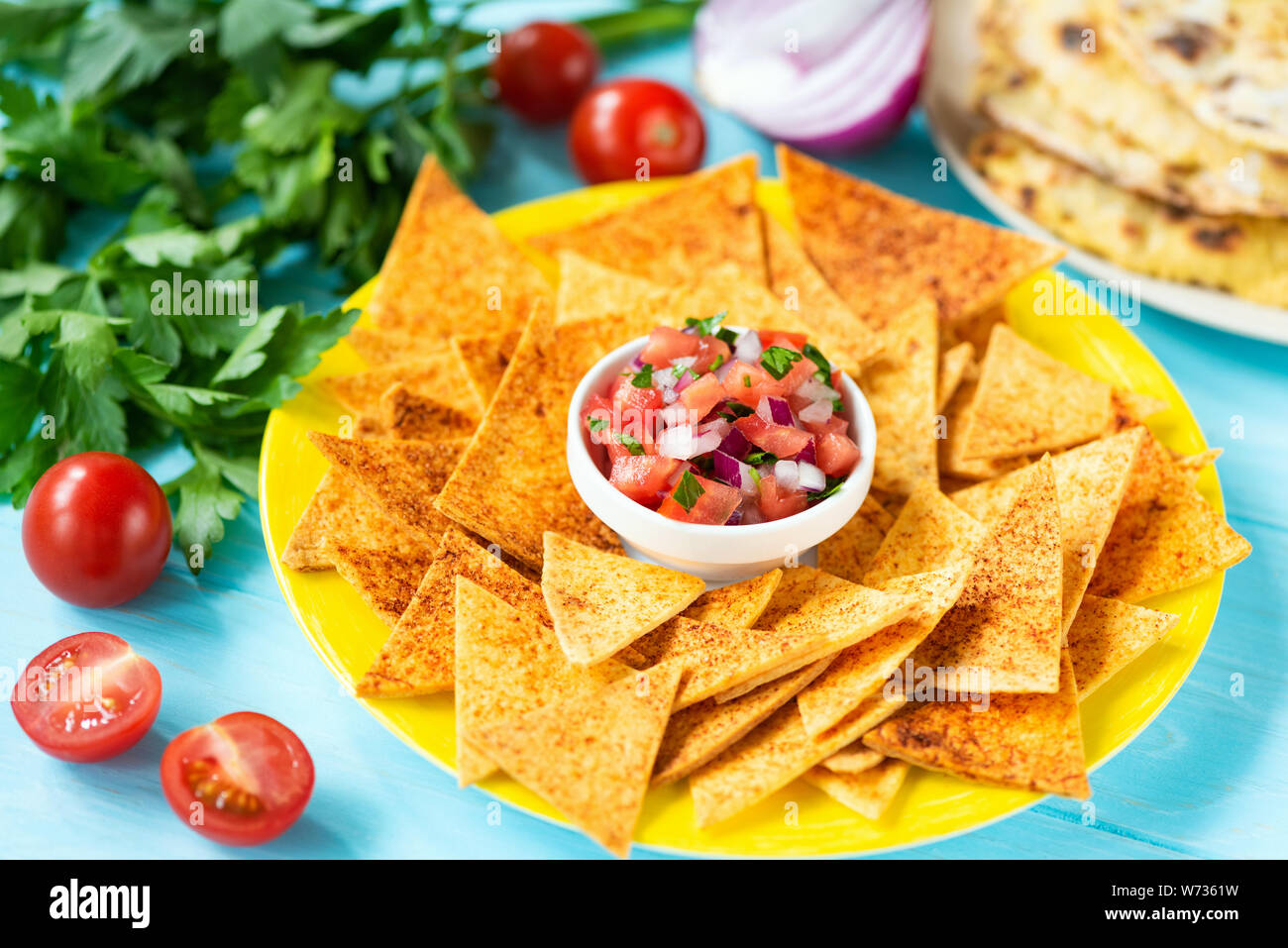 Mais Tortilla Chips, Nachos mit Paprika und Tomaten Salsa auf Platte, blauen Hintergrund. Traditionelle mexikanische Nahrung Tex Mex Stockfoto