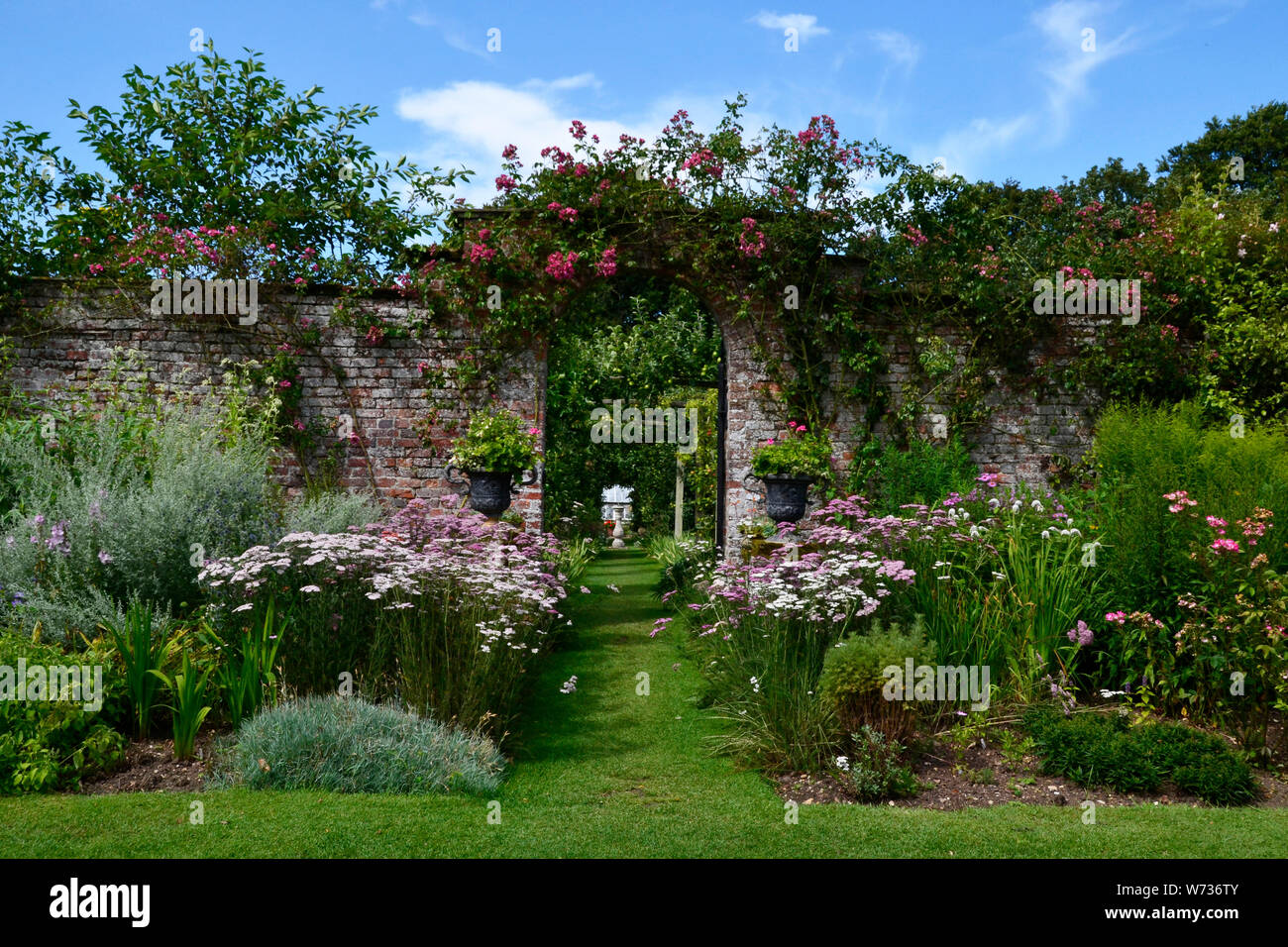 Torbogen und floralen Grenzen in einer typisch englischen Country Garden, Großbritannien Stockfoto