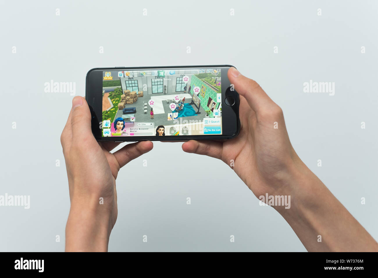 Samara, Russland-07, 29, 2019: ein junger Kerl spielt eine SIMS Spiel auf dem Iphone 8 Plus. Teenager hält ein Handy in der Hand mit einem Spiel Sims Mobile auf dem wh Stockfoto