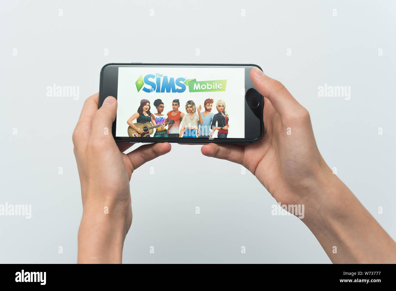 Samara, Russland-07, 29, 2019: ein junger Kerl spielt eine SIMS Spiel auf dem Iphone 8 Plus. Teenager hält ein Handy in der Hand mit einem Spiel Sims Mobile auf dem wh Stockfoto