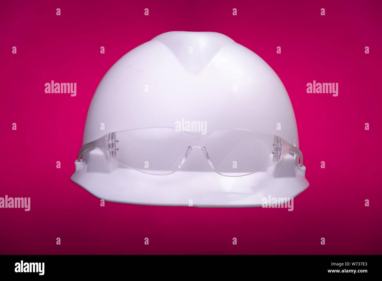Weiß allgemeine Schutzmaßnahmen bau Helm mit transparenten Gläser und Pink Studio Hintergrund. Inclusive Thema Vielfalt und Toleranz Stockfoto