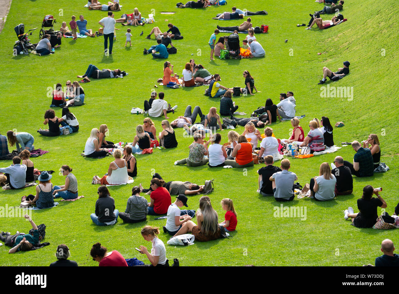 Leute sitzen auf Rasen an die Princes Street Gardens in warmen Sommerwetter in Edinburgh, Schottland, Großbritannien Stockfoto