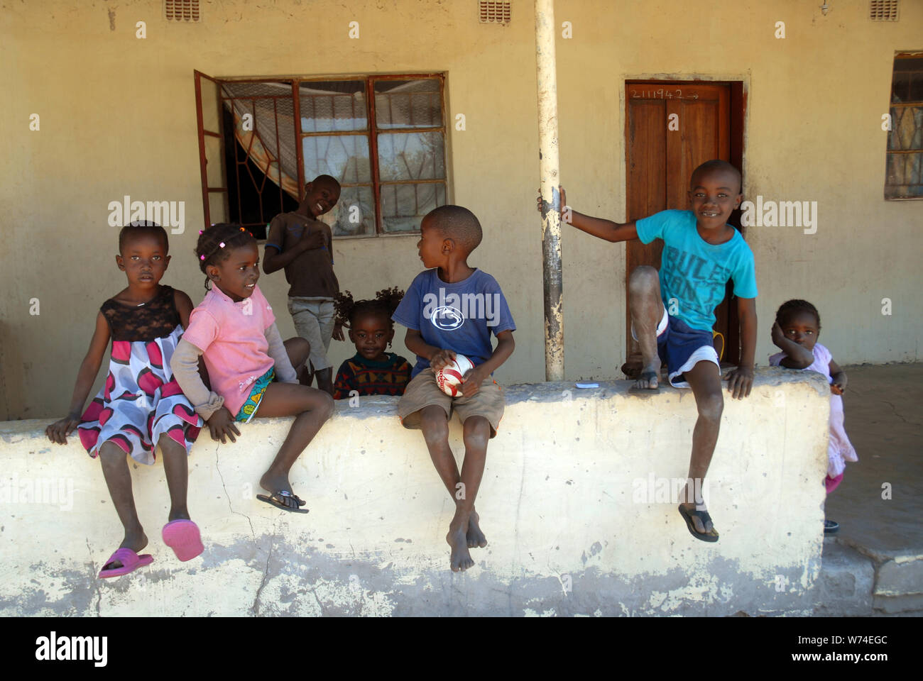 Jungen und Mädchen saßen auf einer Wand, Mwande, Sambia. Stockfoto