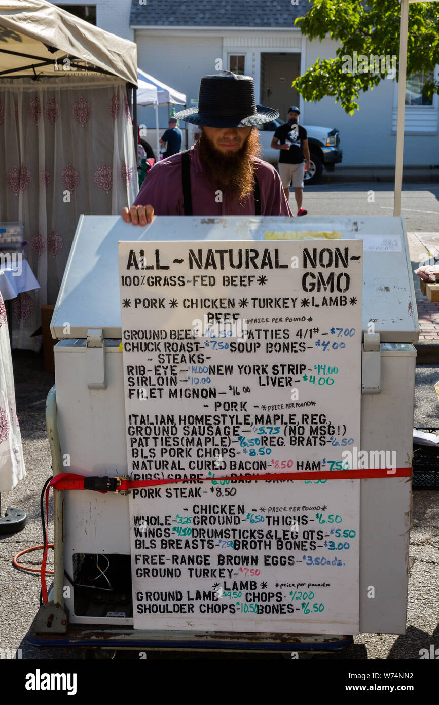 Ein Amish Anbieter hinter einem Gefrierschrank mit einem Schild mit Werbung Nicht-GVO-Fleisch und Eier auf dem Wochenmarkt in der Innenstadt von Fort Wayne, Indiana, USA. Stockfoto