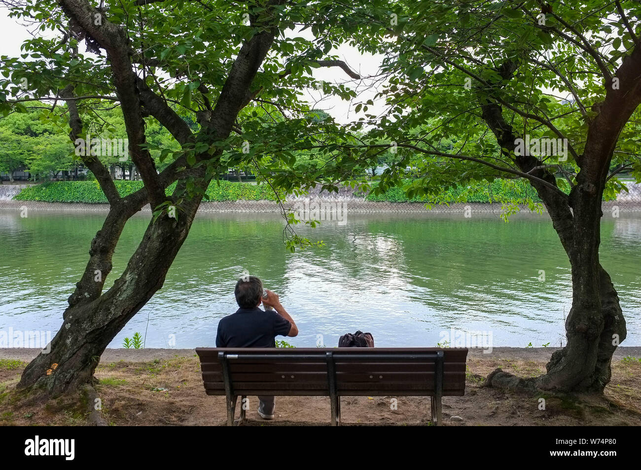 Man trinkt ein Bier entlang der Motoyasu River in Hiroshima, Japan. Stockfoto