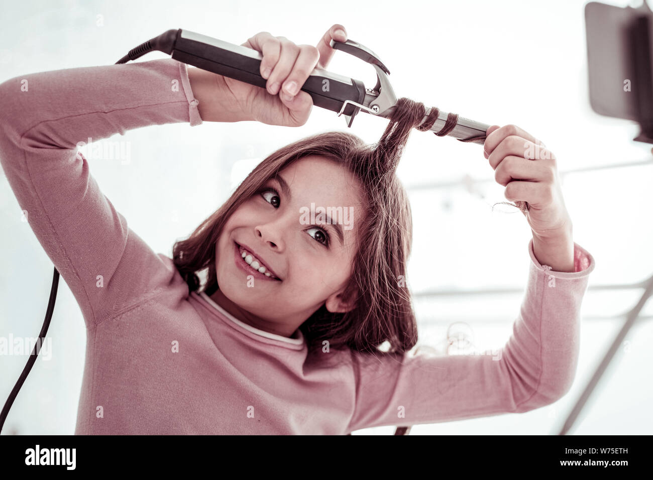 Schönes fröhliches Mädchen mit einem Lockenstab Stockfoto