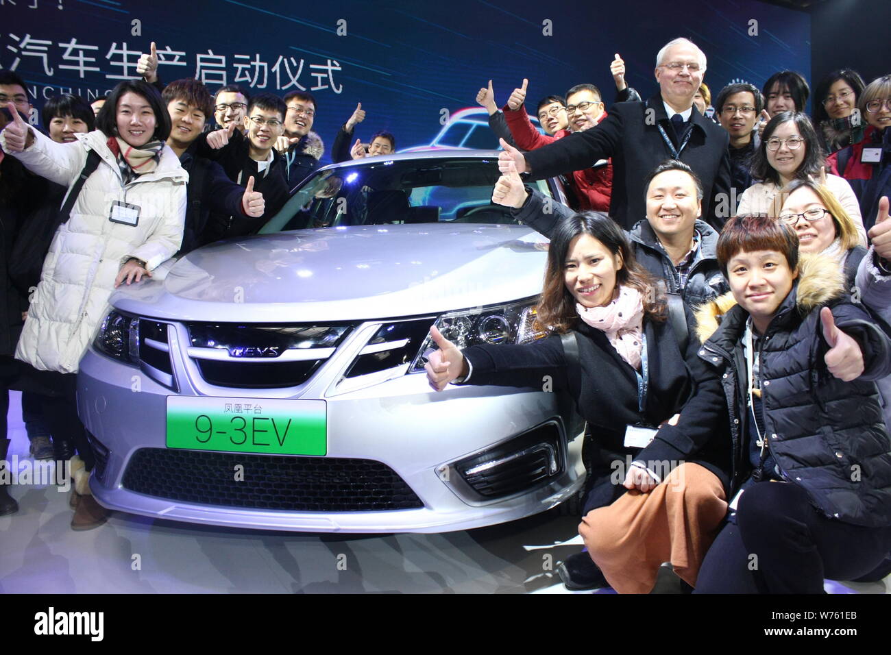 Besucher posieren mit den ersten NEVS 9-3 Serie EV der Nationalen Elektrofahrzeug Schweden während der Off-line-Zeremonie in Tianjin Binhai Hi-tech-Industrie Stockfoto