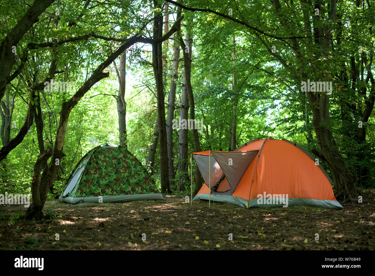Zelten - zwei Zelte - eine orange und eine Tarnung Zelt unter den Eichen  Stockfotografie - Alamy