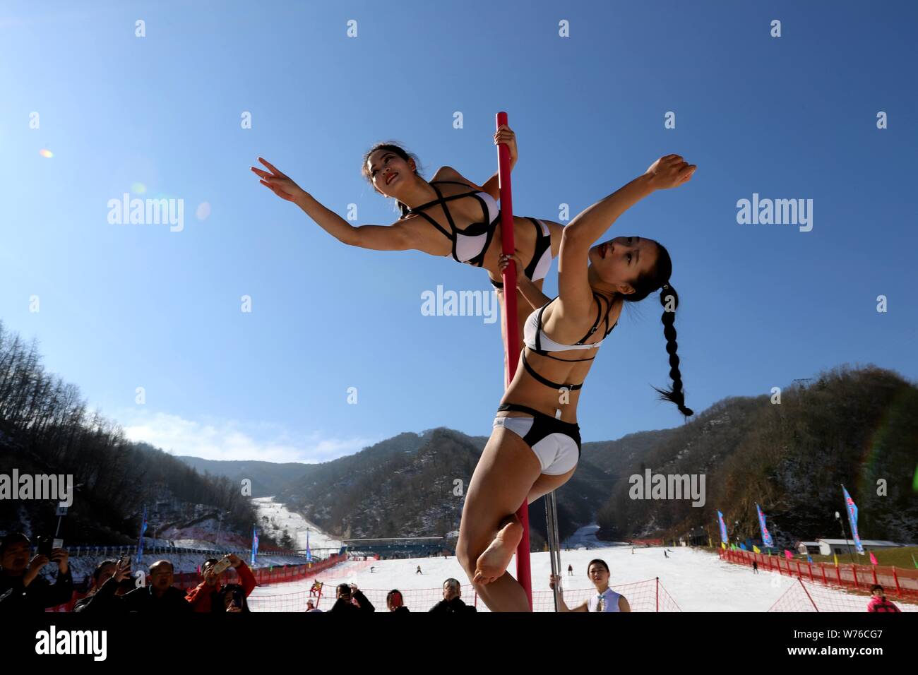 Chinesische Mädchen tragen Bikinis durchführen Pole Dance vor Kälte an einem Ski Park in Luanchuan County, Luoyang City, Central China Provinz Henan, 3. Dezember Stockfoto