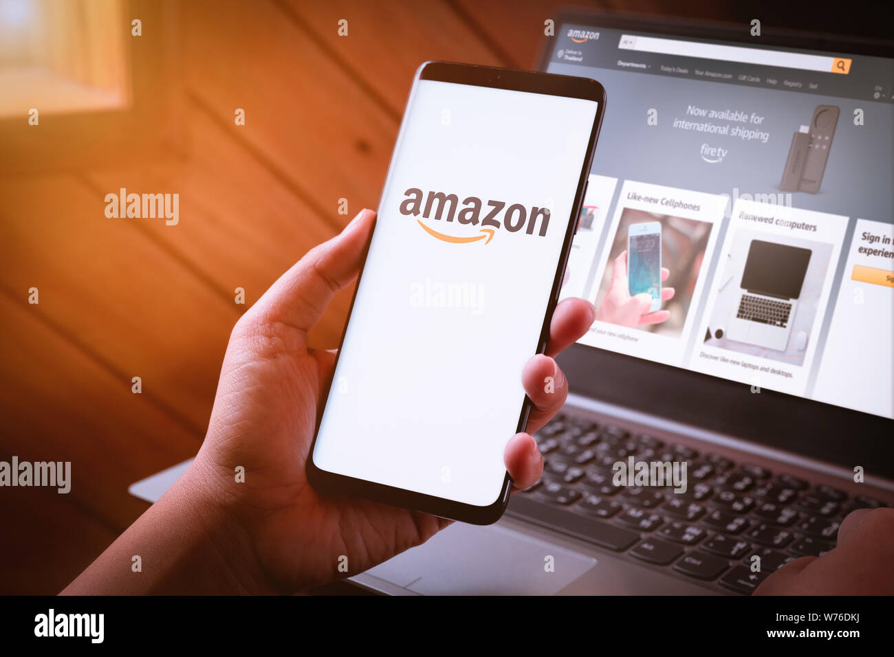 Bangkok, Thailand - August 5, 2019: Frau Hände halten Smartphone mit Amazon Logo auf dem Bildschirm und Amazon Website auf Laptop Hintergrund. Amazon.com, Inc. Stockfoto