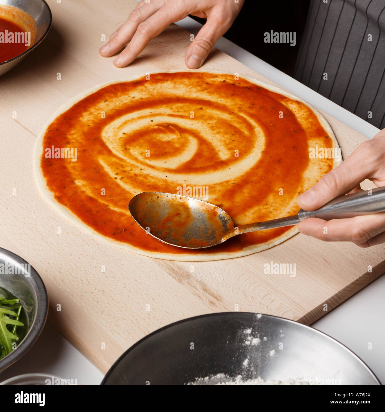 Mann hinzufügen Tomatensauce auf Pizza, Nahaufnahme Stockfoto