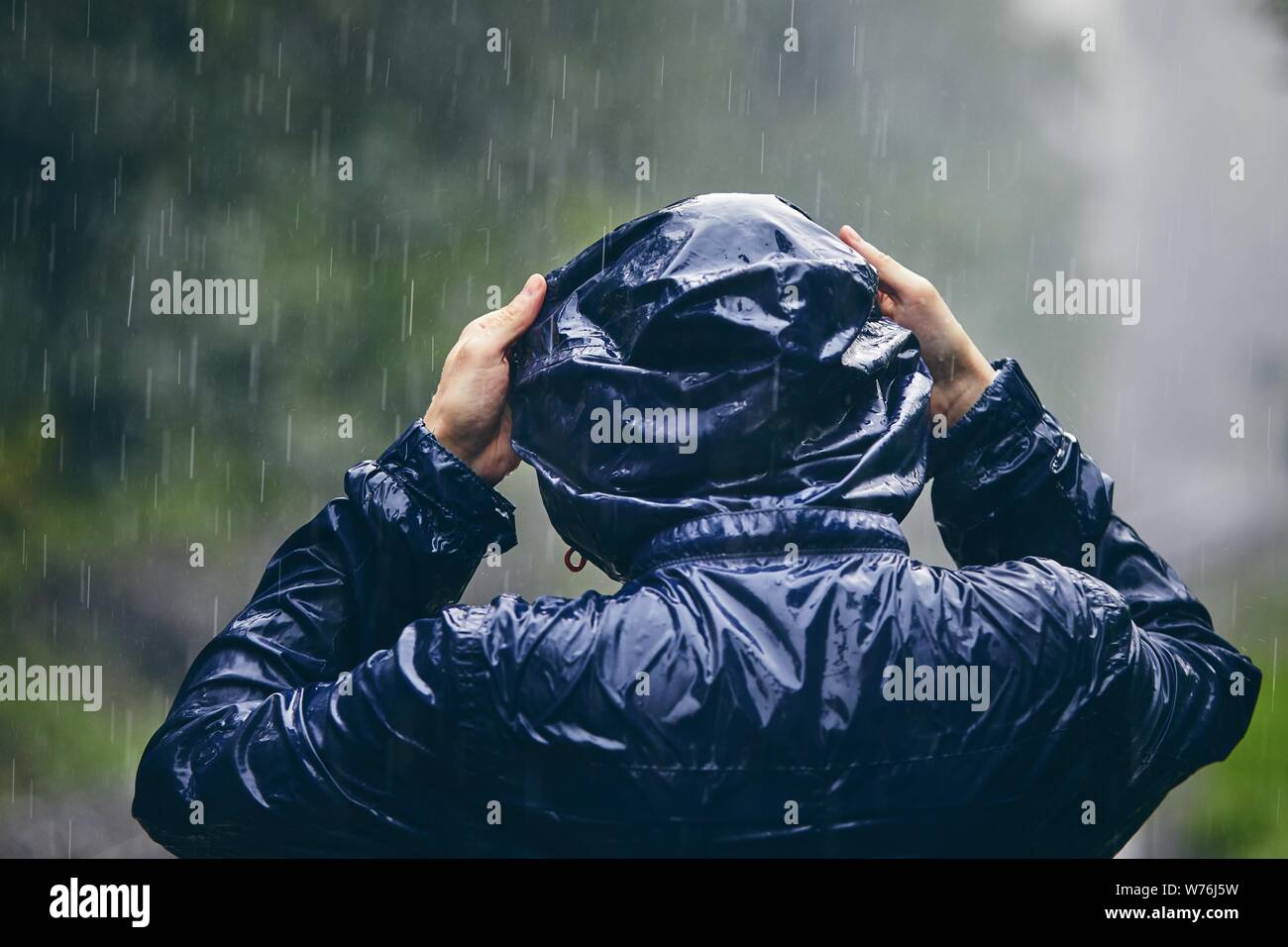 Reise bei schlechtem Wetter. Ansicht der Rückseite des jungen Mannes in Durchnäßte Jacke im starken Regen. Stockfoto