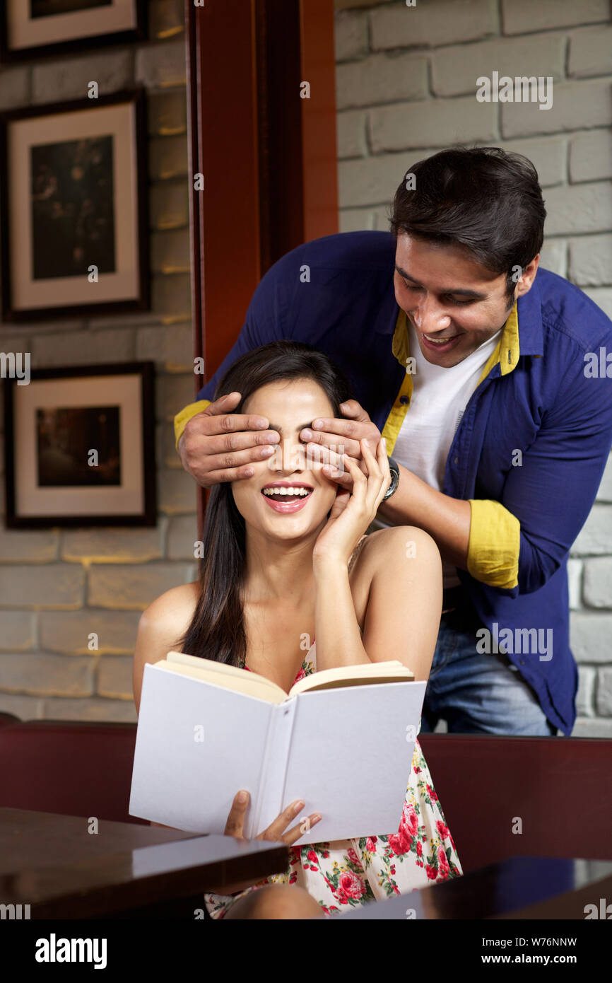 Junger Mann für Augen seiner Freundin in einem restaurant Stockfoto