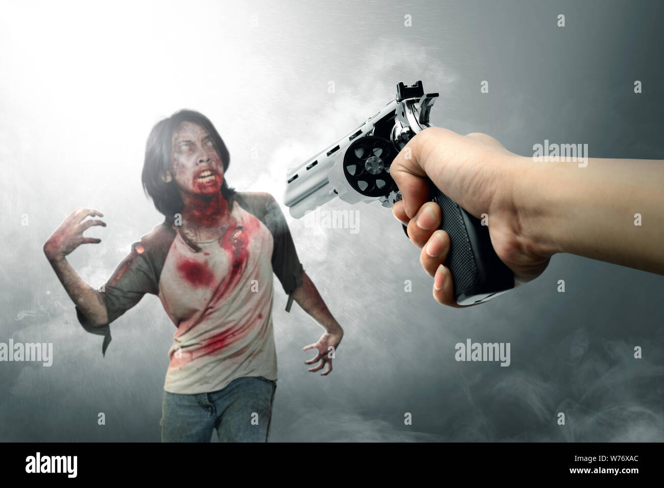 Hände mit einer Pistole Gesicht die Zombies inmitten der Nebel. Halloween Konzept Stockfoto