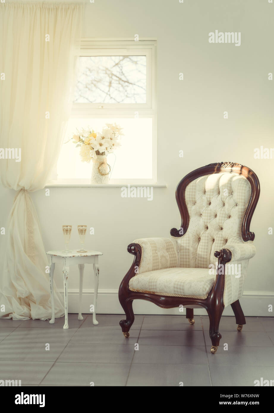 Zwei Gläser champagen in einem Zimmer mit einem bequemen Stuhl und Vase mit Blumen Stockfoto