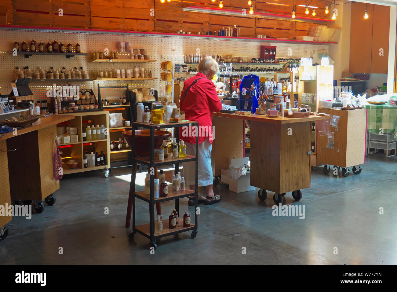 Blonde Frau im roten Mantel Shopping in einer Badewanne Shop am Markt, New Westminster, British Columbia, Kanada. Stockfoto