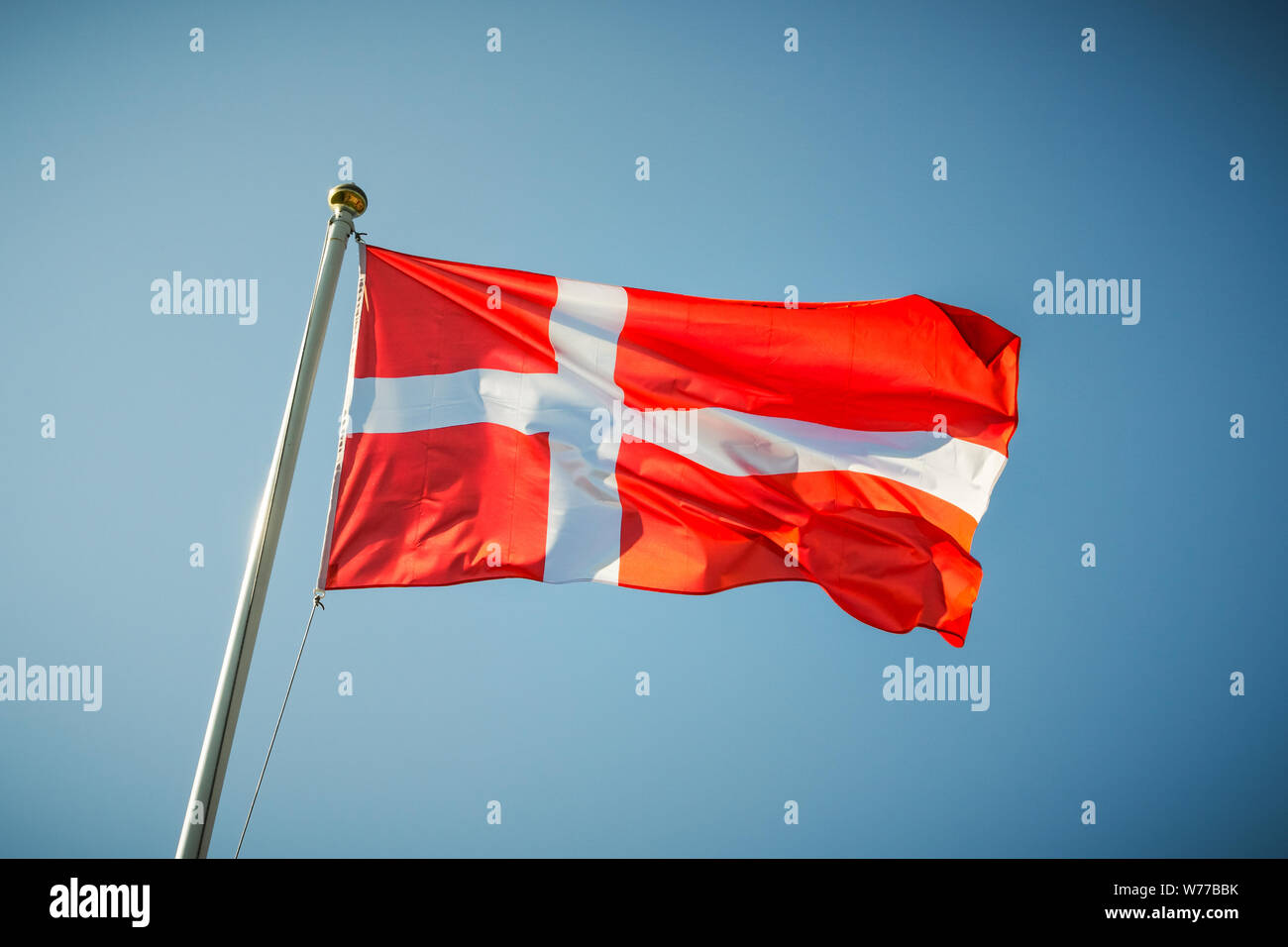 Dänemark Flagge schwenkten auf einen blauen sonnigen Himmel. Stockfoto