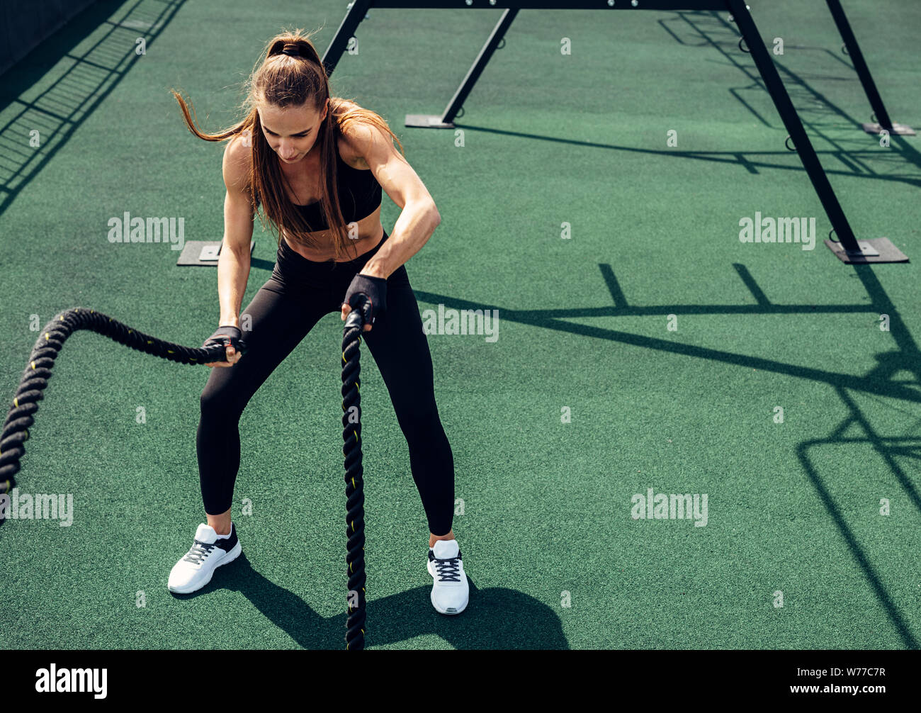 Junge muskulöse Frau Trainieren mit Schlacht Seile auf der Dachterrasse. Frauen, die im Freien arbeiten mit Seilen. Stockfoto