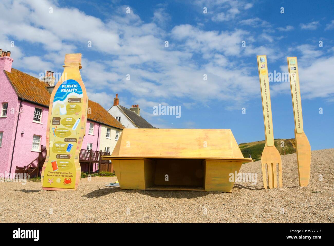 West Bay, Dorset, Großbritannien. 5. August 2019. UK Wetter. Eine Kunstinstallation in der Form einer Plastikflasche, ein fast food Container und Messer und Gabel für einen Kunststoff Recycling Kampagne am Strand am Strand von West Bay in Dorset an einem heißen sonnigen Tag. Bestehend aus 8 Fuß hoch Kunststoff Trinkflasche, Besteck 6 Fuß hoch und einem Chip/burger Box 4 x 4 Fuß die Skulpturen die Bemühungen der Wurf frei Küste und Meer und Partner bei der Förderung ökologisch verantwortungsvolle Entscheidungen zu fördern. Foto: Graham Jagd-/Alamy leben Nachrichten Stockfoto