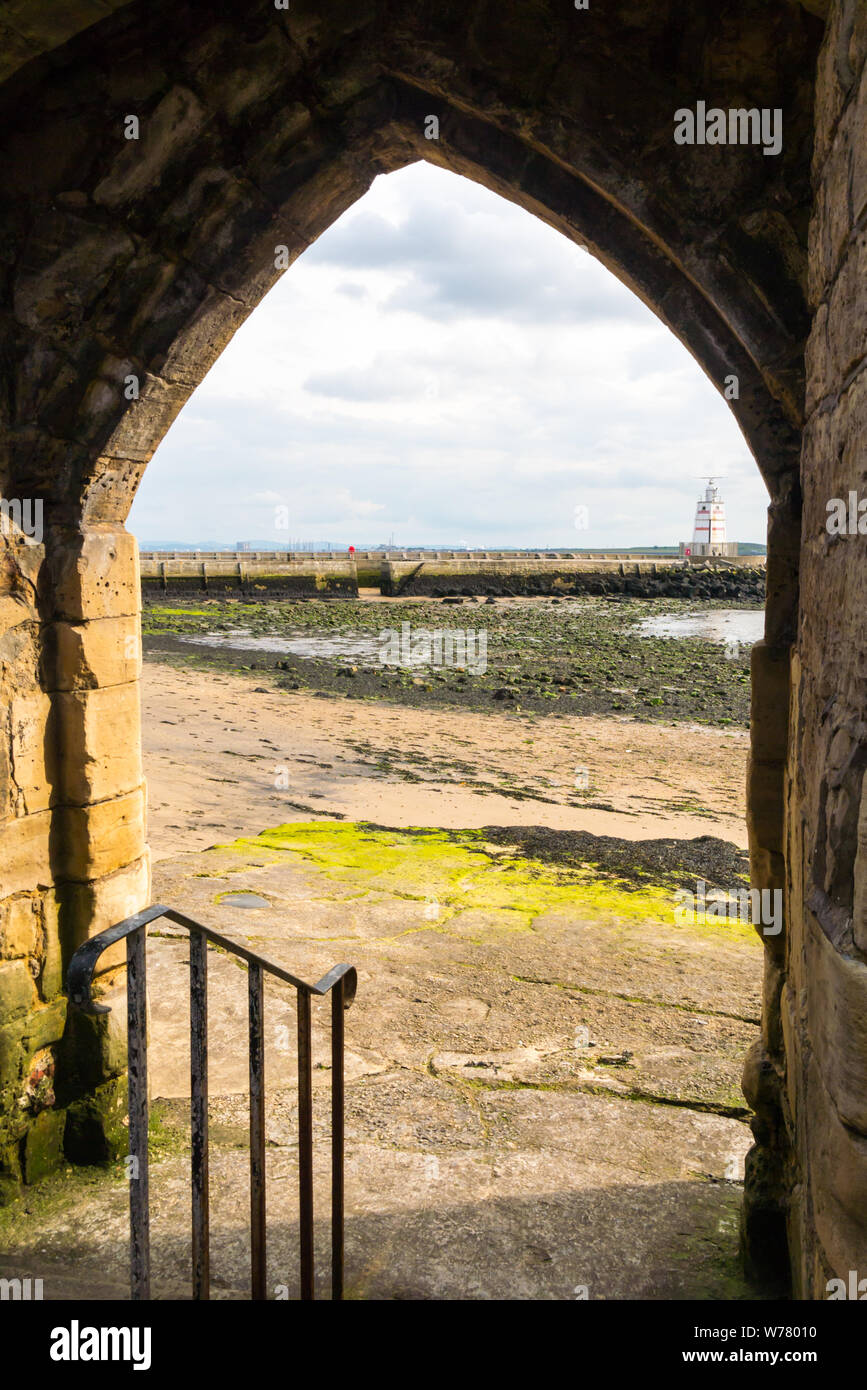 Einen spitzen Kalkstein Torbogen durch Hartlepool Stadtmauer auf den Strand Stockfoto