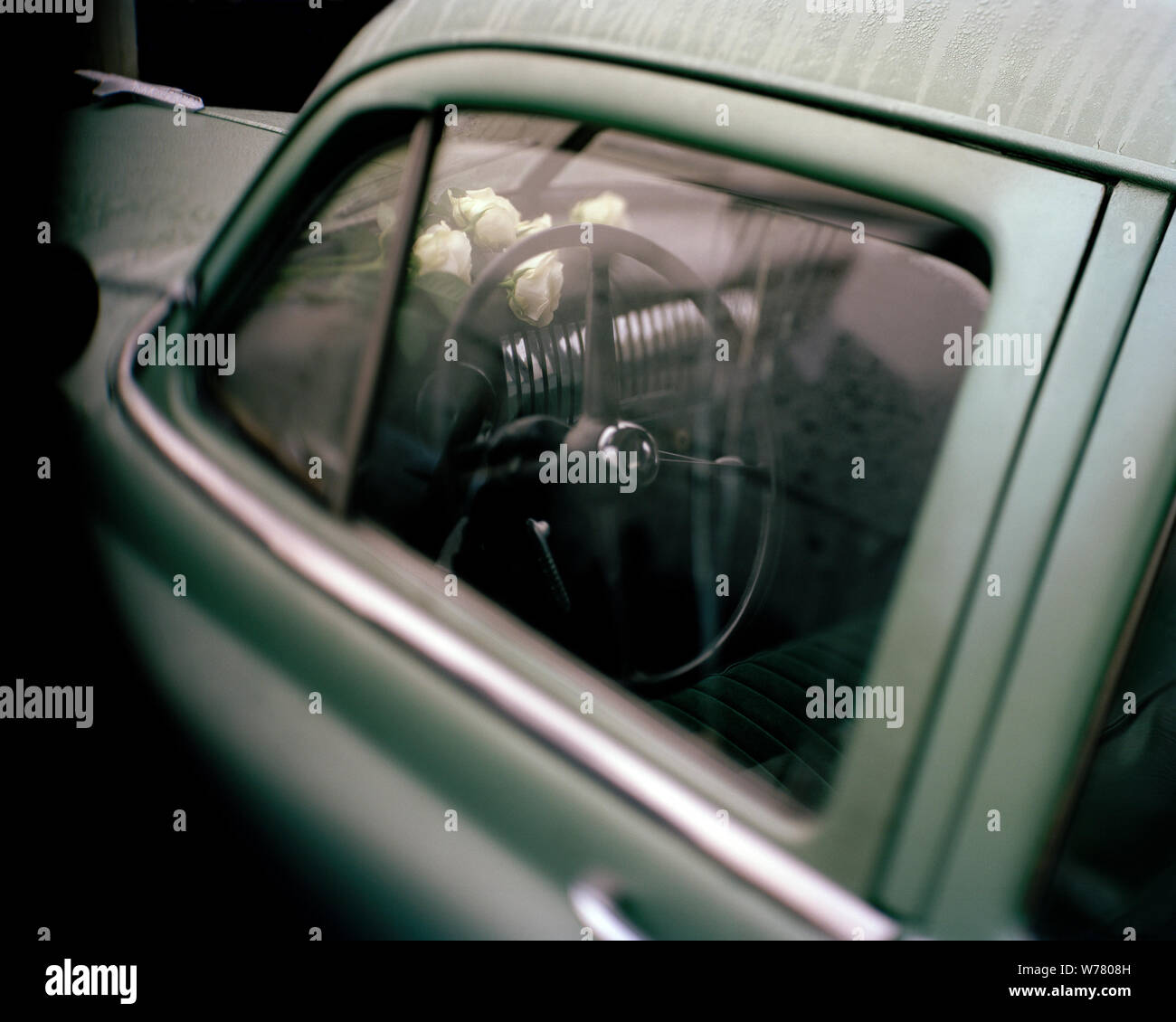 Blick durch das Fenster in einem Oldtimer mit Rosen auf dem Armaturenbrett Stockfoto