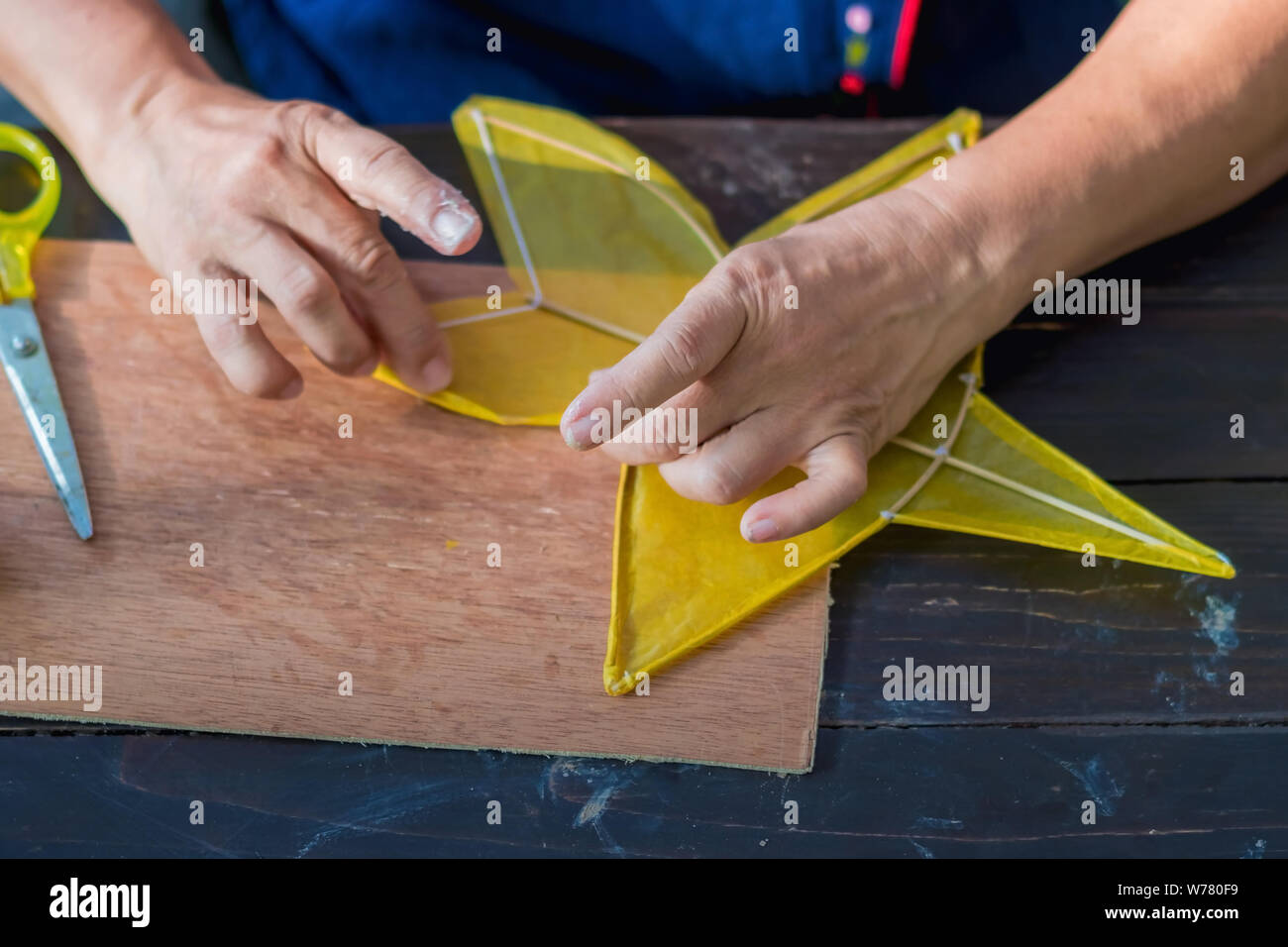 Ältere Frau, und sternförmige Kite oder Thai name Chula Kite für den Verkauf am lokalen Markt zu errichten. Selektiver Fokus auf der linken Finger. Stockfoto