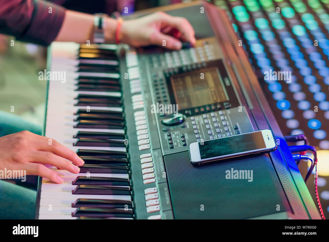 Musiker spielen elektronisches Keyboard Synthesizer, indem Sie ihr  Smartphone als Leitlinien für das Spielen auf der Bühne. Selektiver Fokus  auf dem Smartphone Stockfotografie - Alamy