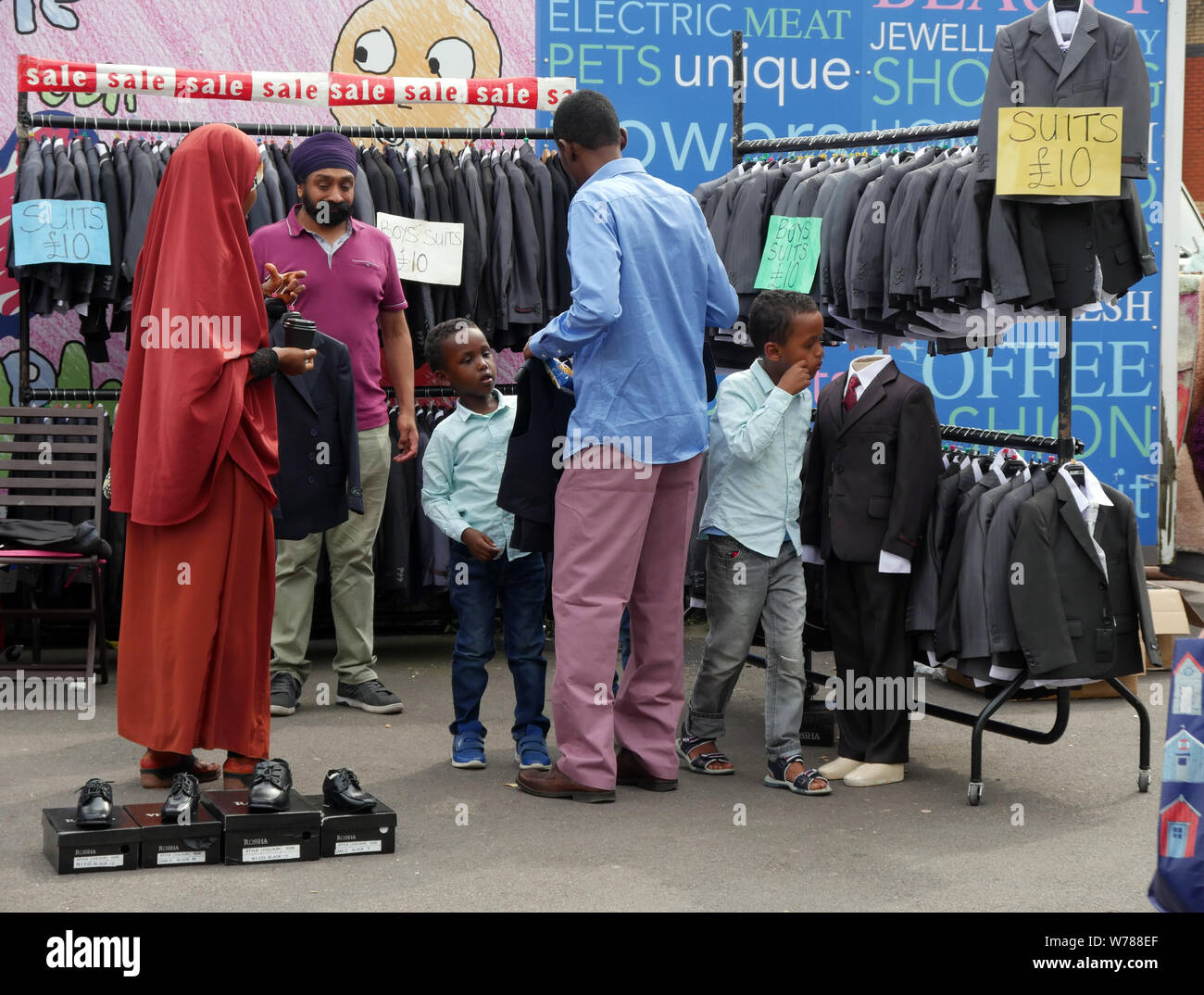 Familie Einkauf für die Jungen Anzüge auf einem Markt im Freien in England Großbritannien, ein Junge versucht, auf eine Jacke, während die Eltern einen Preis verhandeln. foto DON TONGE Stockfoto