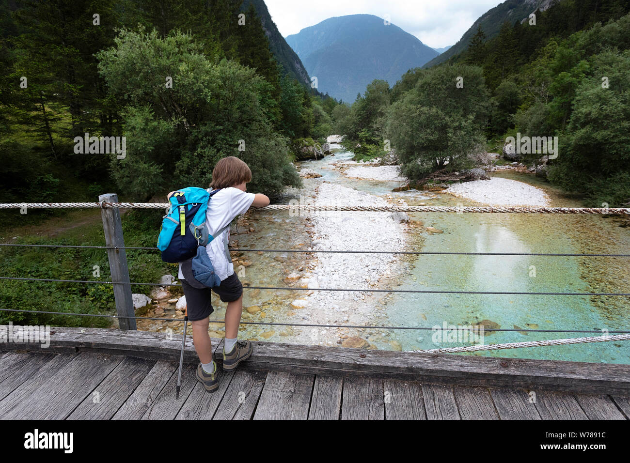 Süße junge Kreuzung eine hölzerne Hängebrücke über schöne türkisblaue Fluss Soca während Trekking auf dem Trail, Bovec Soca, Slowenien, Europa Stockfoto