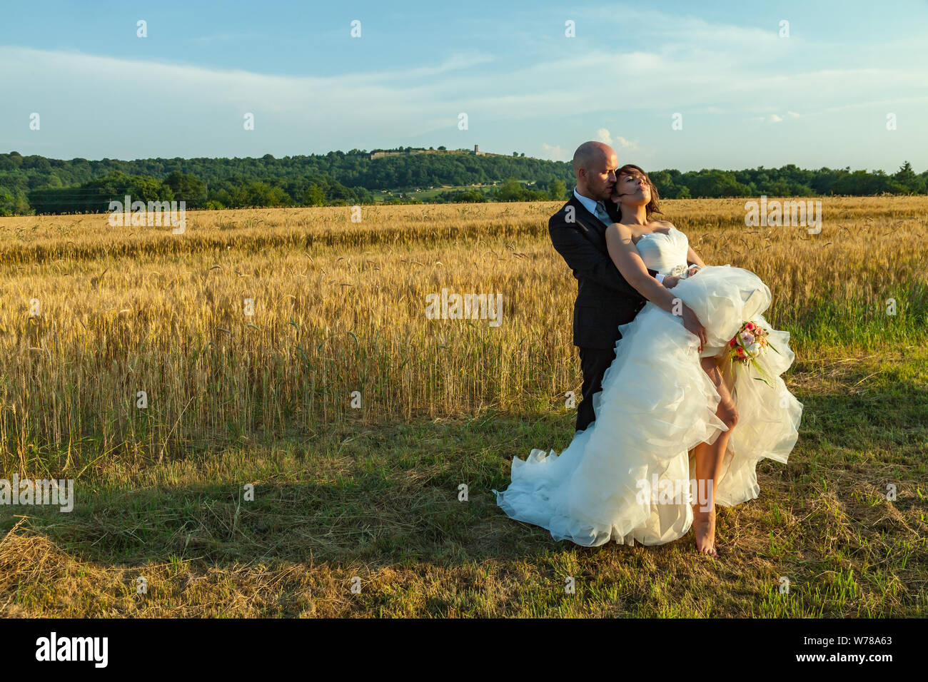 Romantisches Paar in der Hochzeit mit einem Blumenstrauß in einem Weizenfeld Stockfoto