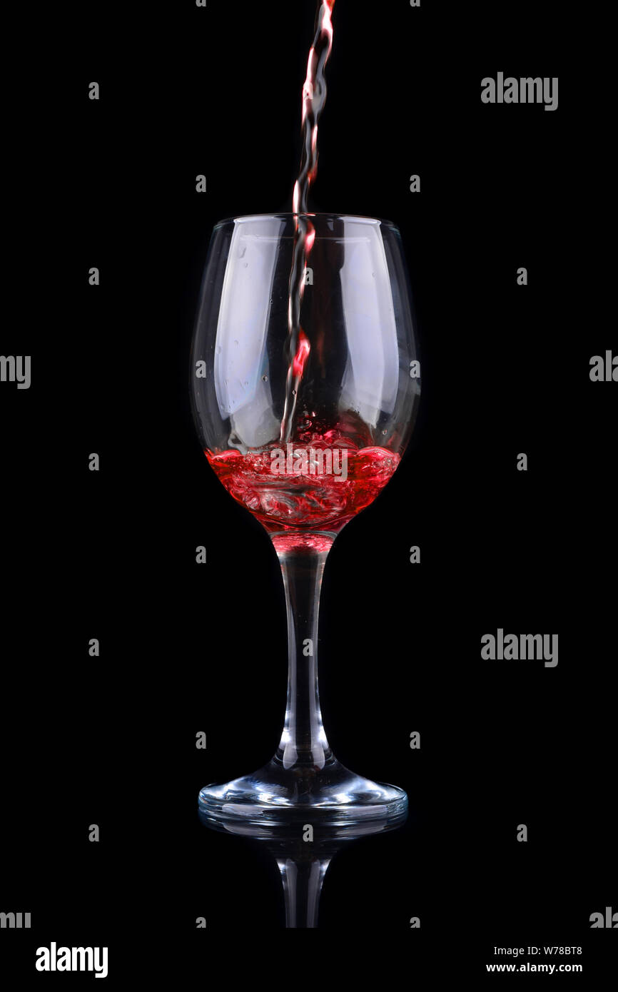 Rotwein in ein Glas Wein einzuschenken. Auf schwarzem Hintergrund Stockfoto