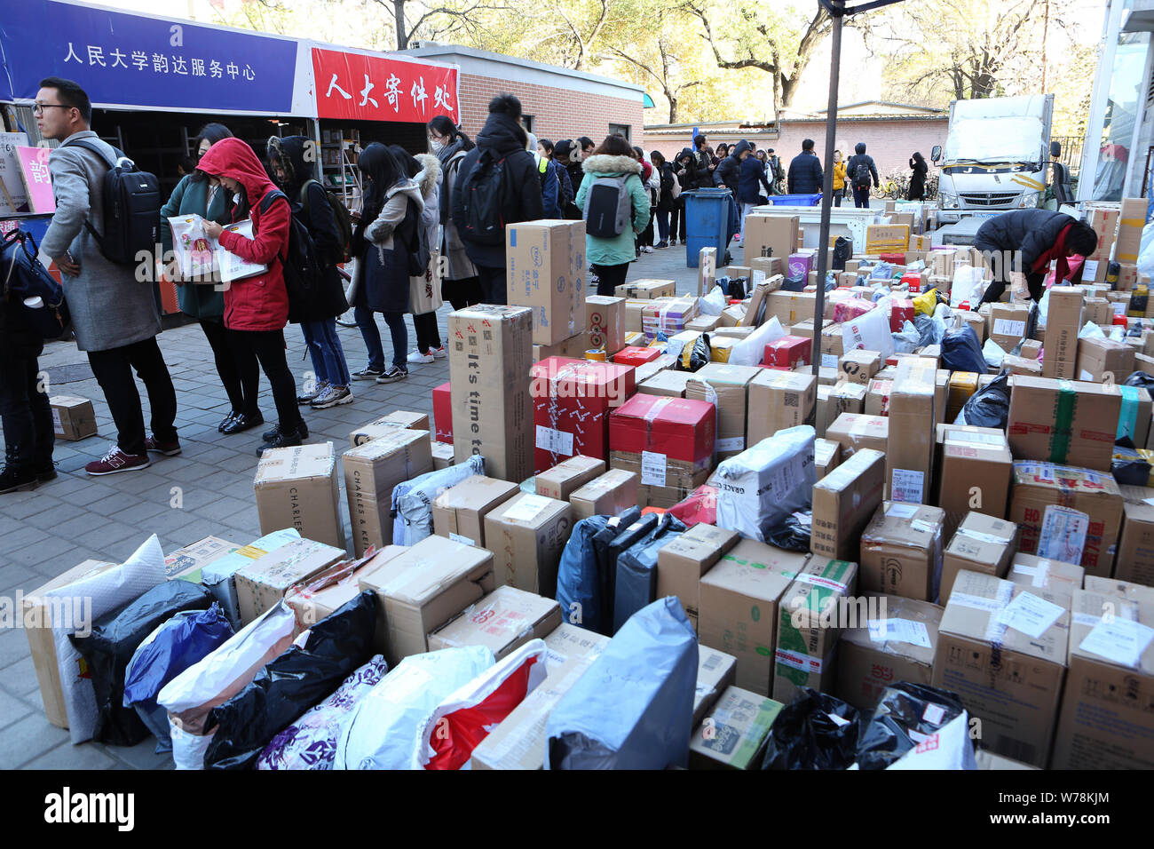 Chinesische Studenten suchen in einer Masse von Parzellen, von denen die meisten von Singles online shopping, bei einem Tor der Renmin Universität in Peking, China Stockfoto