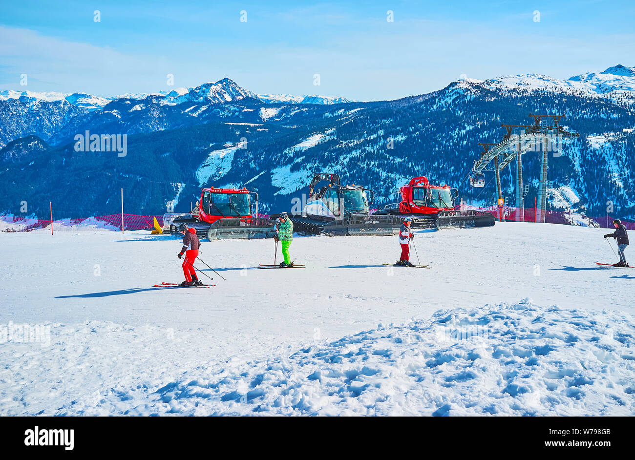 GOSAU, Österreich - 26. FEBRUAR 2019: Die Skifahrer Skate entlang der Neigung der Zwieselalm Berg mit Blick auf geparkten Pistenraupen und Gipfel des Dachsteins Wir Stockfoto