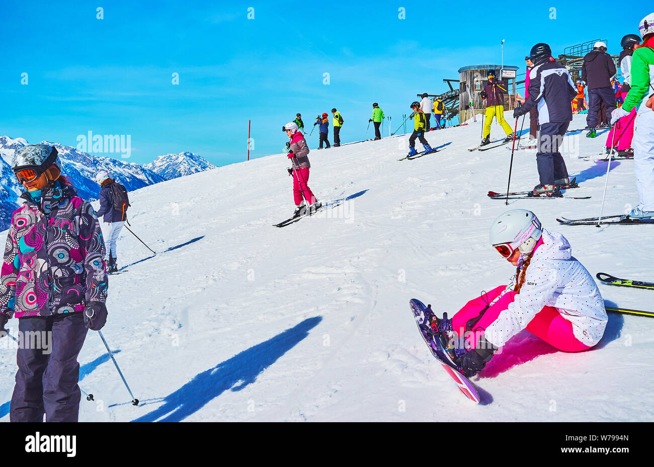 GOSAU, Österreich - 26. FEBRUAR 2019: Die Skifahrer bergab von der Oberseite der Zwieselalm Berg (Dachstein West) und junge Mädchen legt Bindungen von Sno Stockfoto