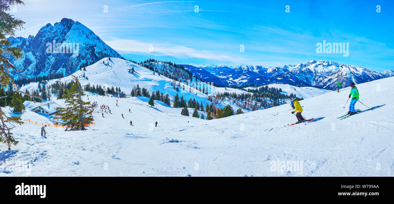 GOSAU, Österreich - 26. FEBRUAR 2019: Panorama der verschneiten Hügel der Zwieselalm Berg mit Ski laufen und Sportler, bergab mit Blick auf Dachste Stockfoto