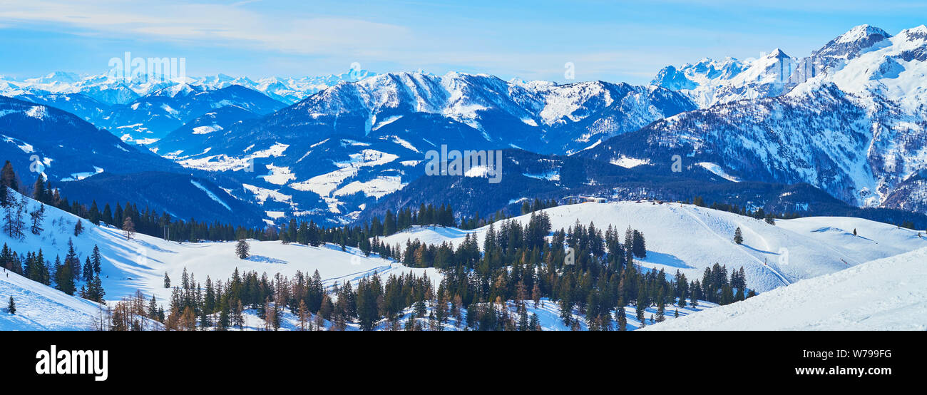 Panorama der Zwieselalm Almwiese, coveredd mit Schnee, Nadelwäldern, Skipisten, Liftanlagen und durch scharfe felsigen Gipfeln von Dachstein Wes umgeben Stockfoto