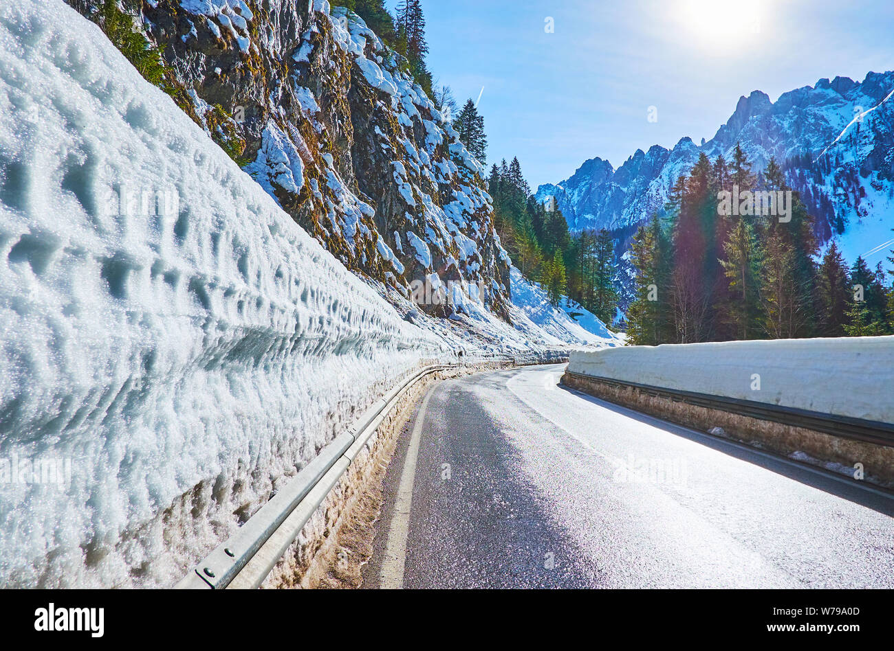 Die leere Straße zwischen Dachstein Alpen, gesäumt von hohen Schnee Wand, Gosau, Salzkammergut, Österreich Stockfoto