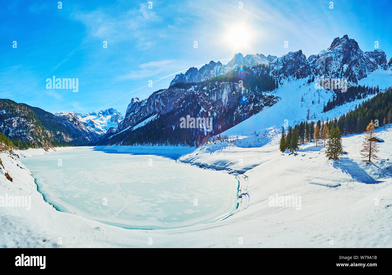 Winter Panorama der Gosausee, mit Eis bedeckt und durch verschneite Pisten von Dachstein Alpen mit üppigen Nadelwäldern und felsigen Gipfeln umgeben, Gosau, Stockfoto