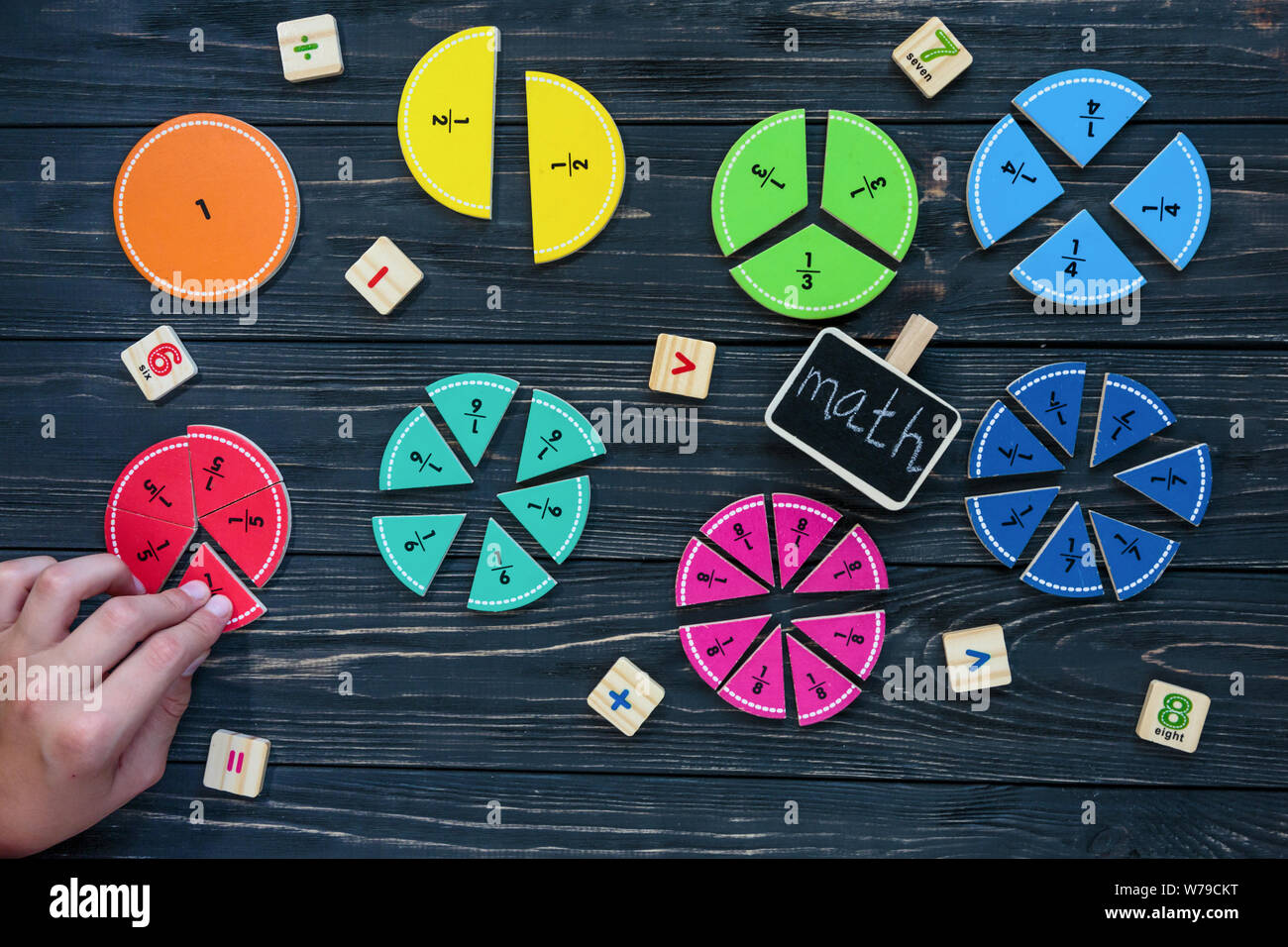 Kinder Hand bewegt sich bunte mathematische Fraktionen auf dunklem Hintergrund oder Tabelle. Interessante kreative lustige Mathe für Kids. Bildung, zurück in die Schule anhand von quantitativen Simulatio Stockfoto